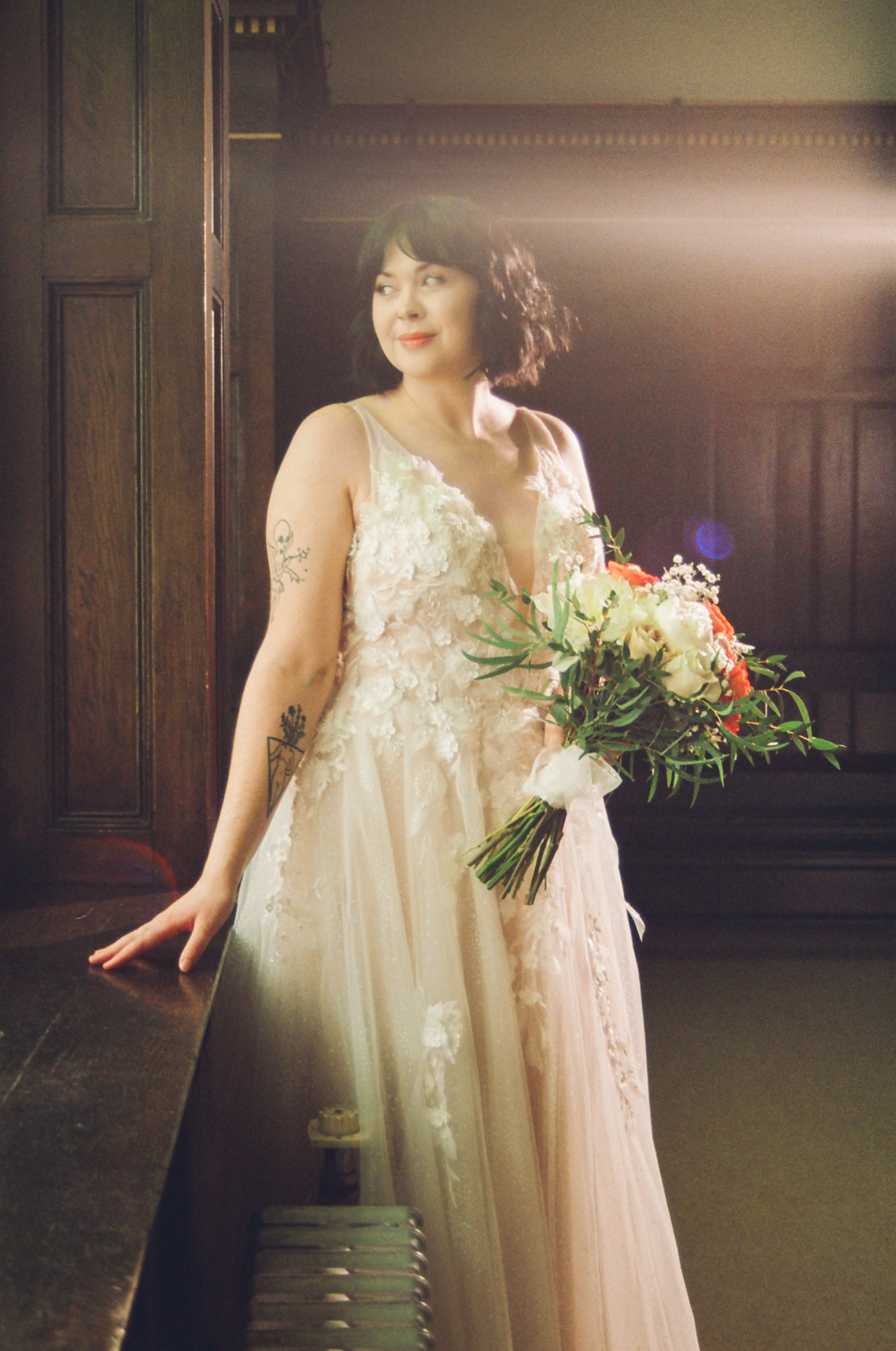 Brooke stands in her wedding dress with bouquet in Kamloops Old Court House, photographed on 35mm film